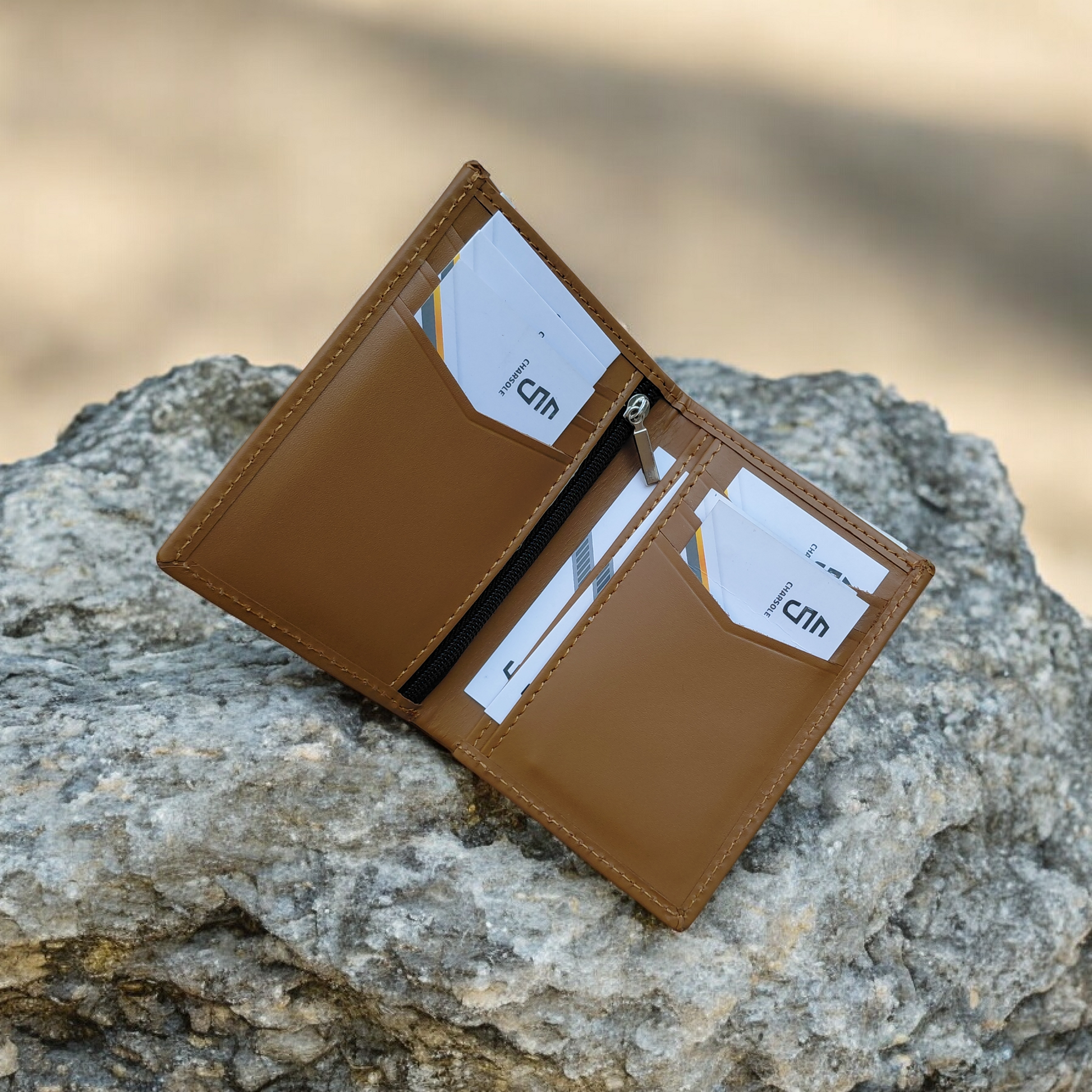 Brown leather wallet with card slots on a rock